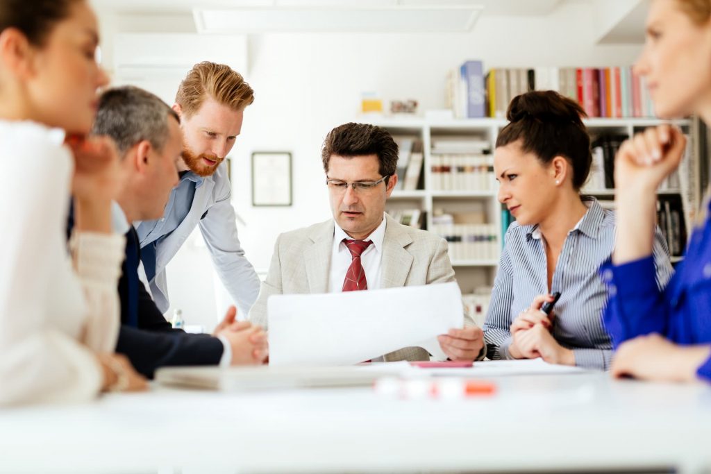 A business team gathered around a table, discussing critical challenges while reviewing a strategic plan