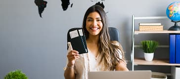 Female sales agent holding plane tickets while smiling making eye contact