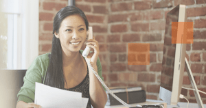 woman smiling while holding a telephone